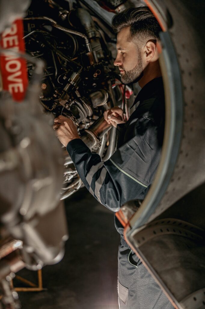 Male airline mechanic repairing aircraft in hangar