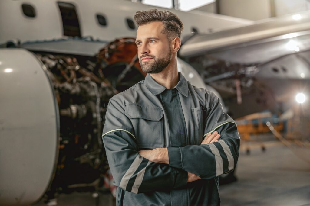 Bearded man aircraft maintenance engineer standing in hangar